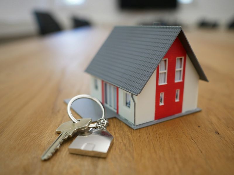 Miniatura de casa com chaves sobre mesa de madeira